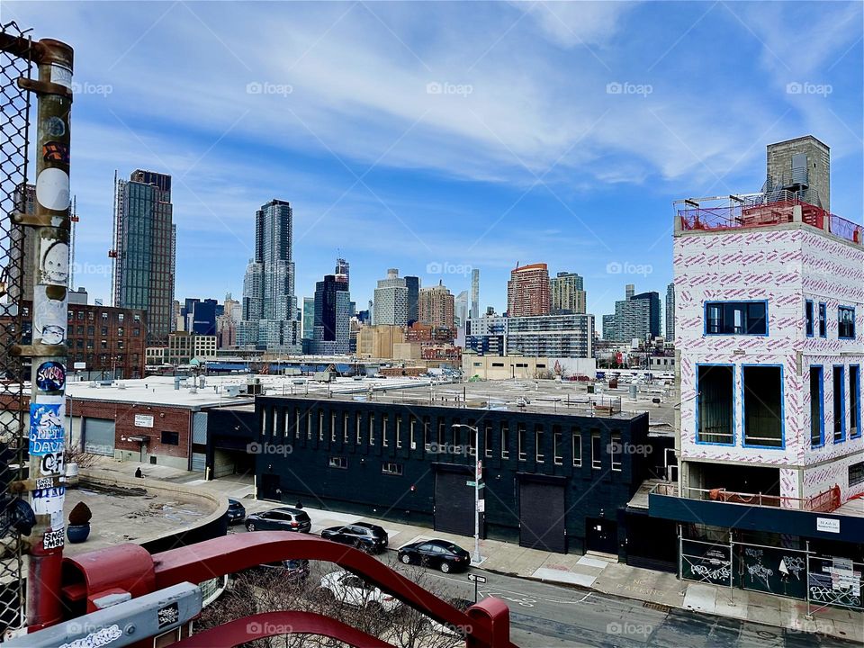 This is the view from the top of the red metal staircase of the „Pulaski Bridge“ at „Newtown Creek“ in „Greenpoint“, Brooklyn. In the far distance we see the „Manhattan“ skyline. 2024. Hypnotic Productions