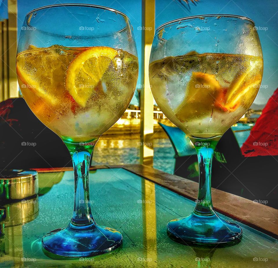 two glass bowls with gin and tonic, ice and lemon