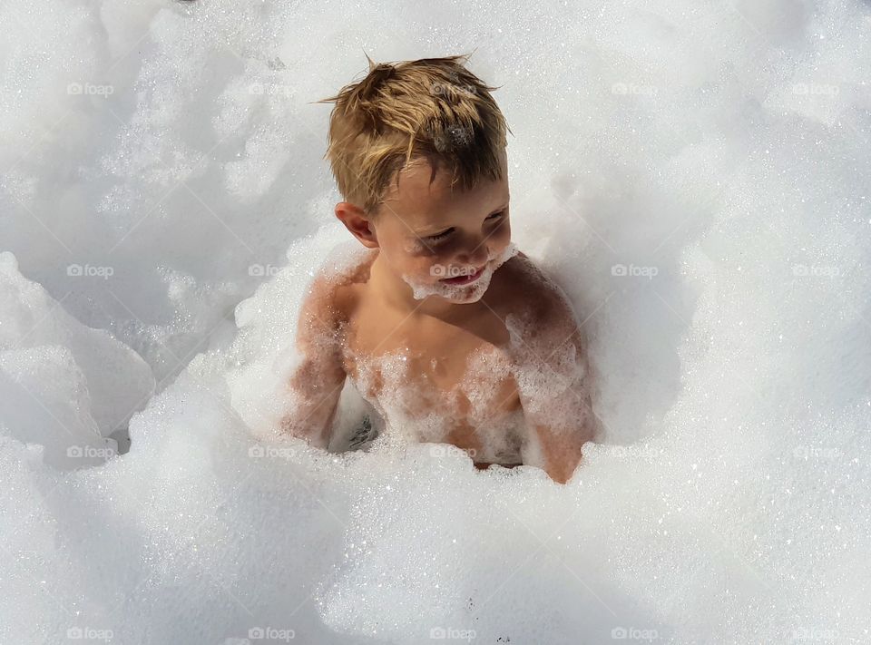 Little blond boy sitting in foam