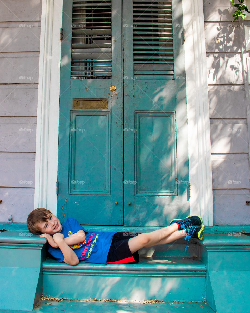 Young boy laying in doorway of a New Orleans shotgun house 