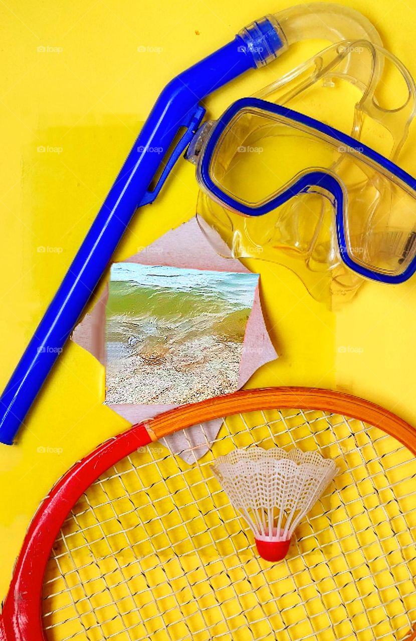 On a yellow background are items for outdoor activities at sea: a tennis racket with a shuttlecock and a snorkel with a mask for scuba diving.  In the middle is a "window" in which the view of the seashore and waves