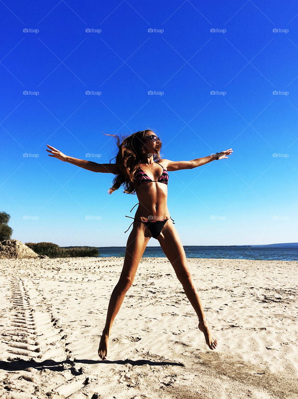 Young woman with long hair and fitness figure on the summer beach 