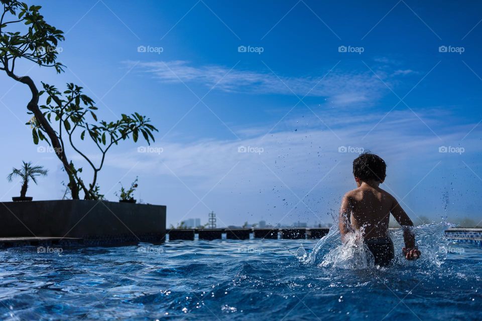 Little Boy playing in the pool on summer day