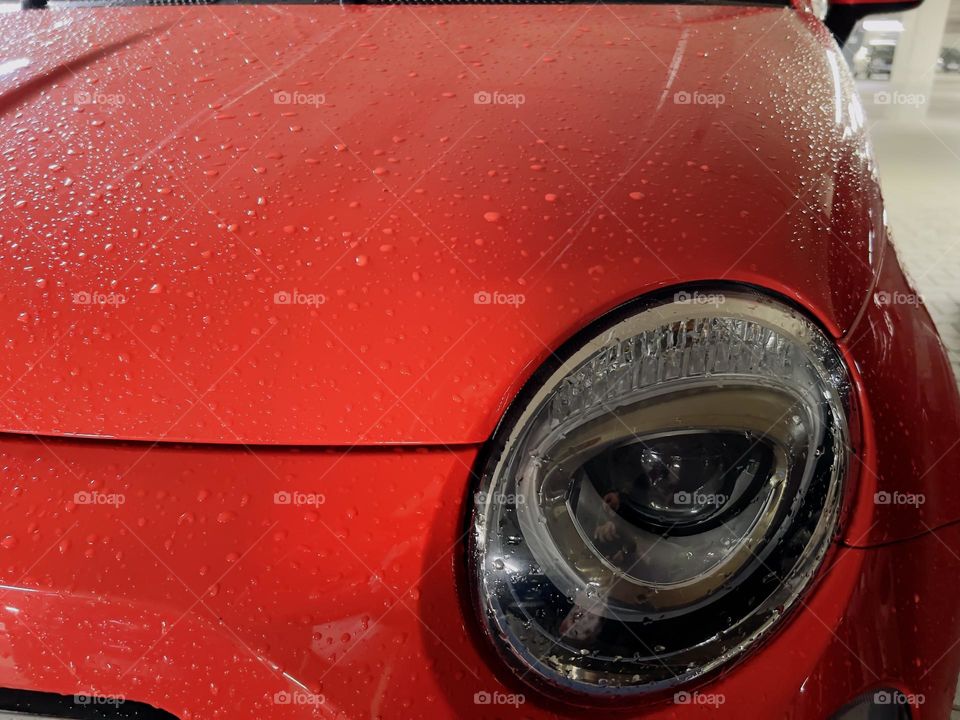 Wet red car with front light