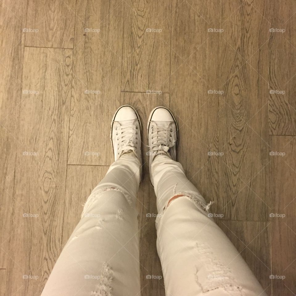 White sneakers on girl legs on wooden background great for any use.