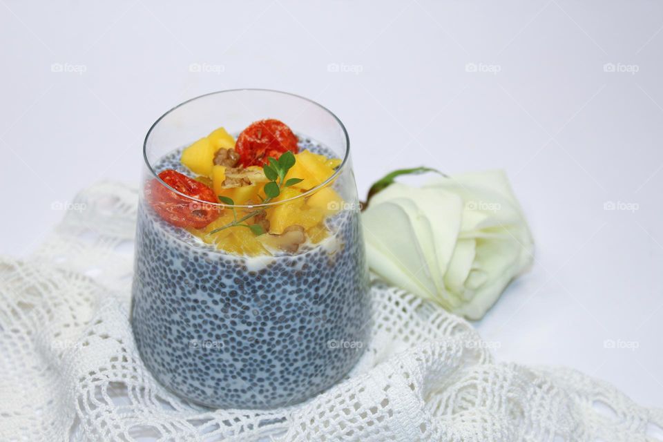 Healthy and tasty dessert.  Chia pudding with mango in a glass cup on a white background