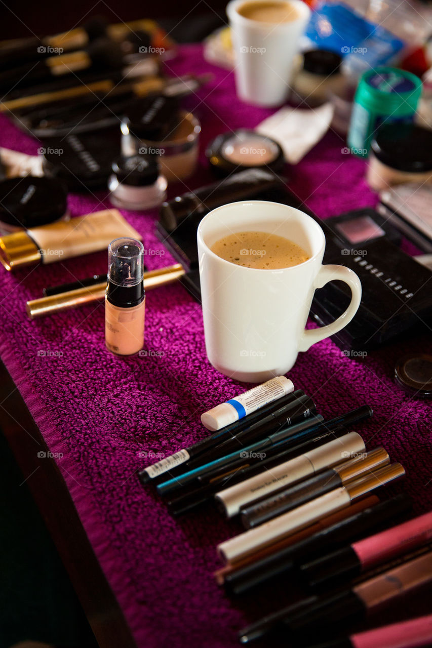 Working makeup artist with cup of coffee. Love the purple backdrop for the makeup setting.