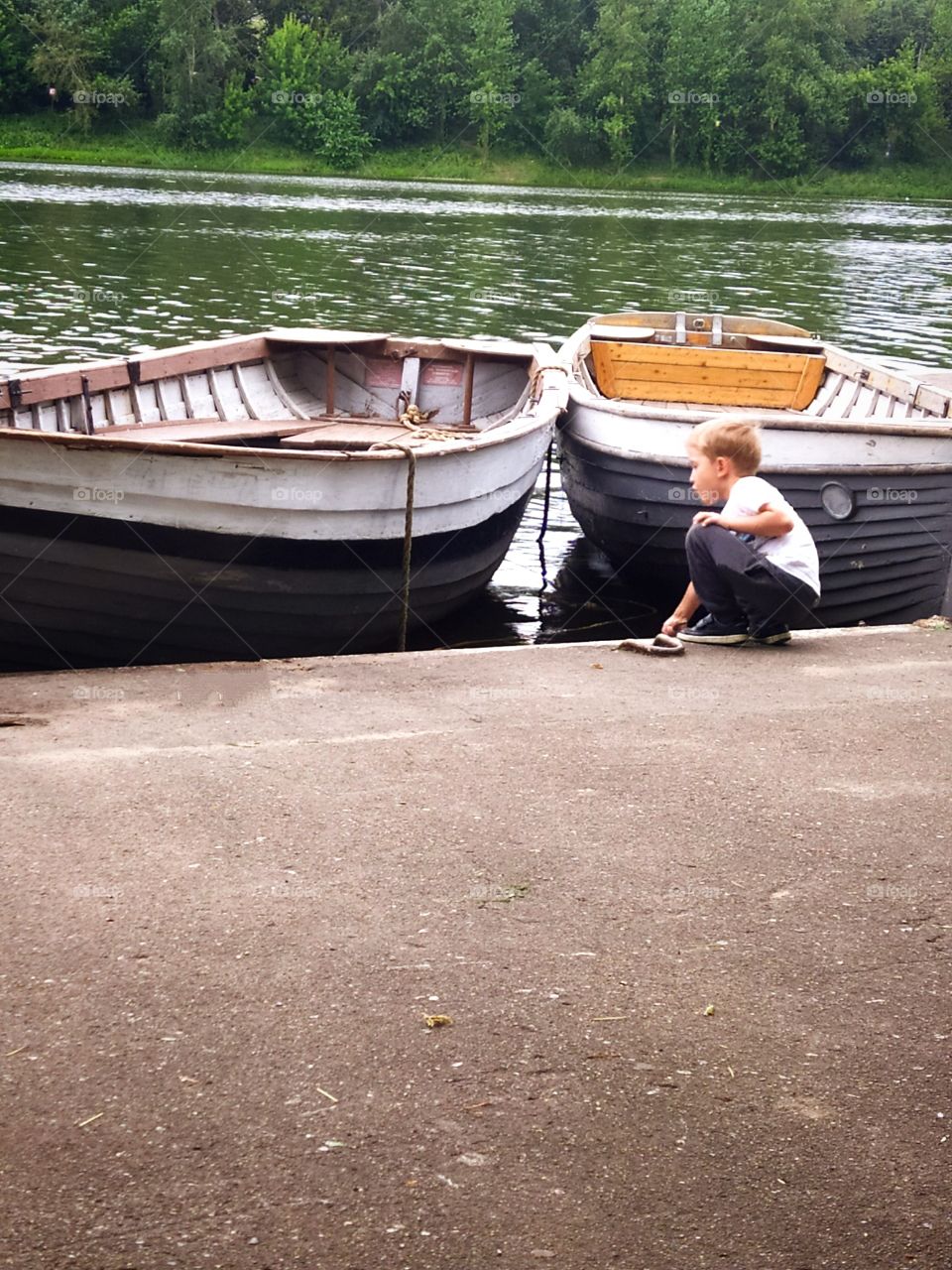 Boy playing with water near two boats