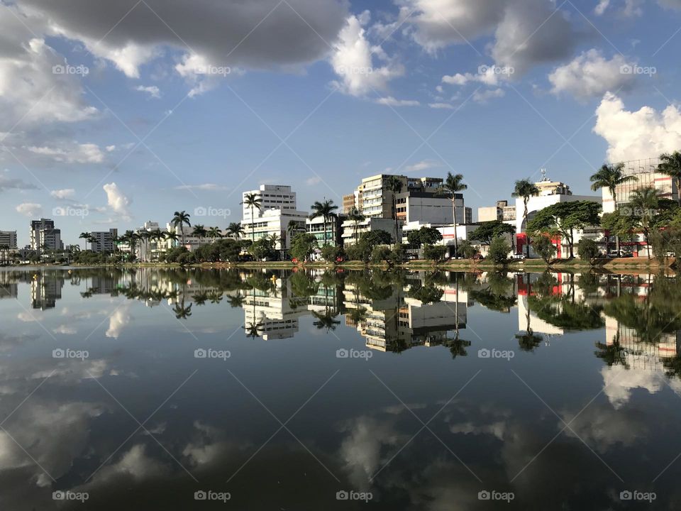 Central Lake in Sete Lagoas, a city in the southeast of Brazil, where one can see the clear reflex of the buildings and palm trees around in a bright fall afternoon