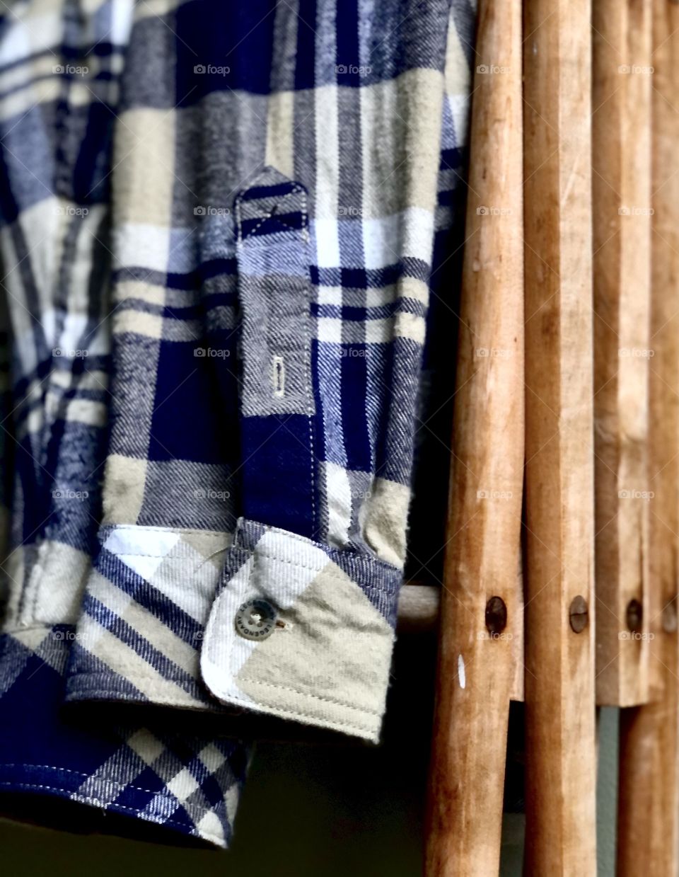 Blue plaid flannel shirt on wooden clothes rack 