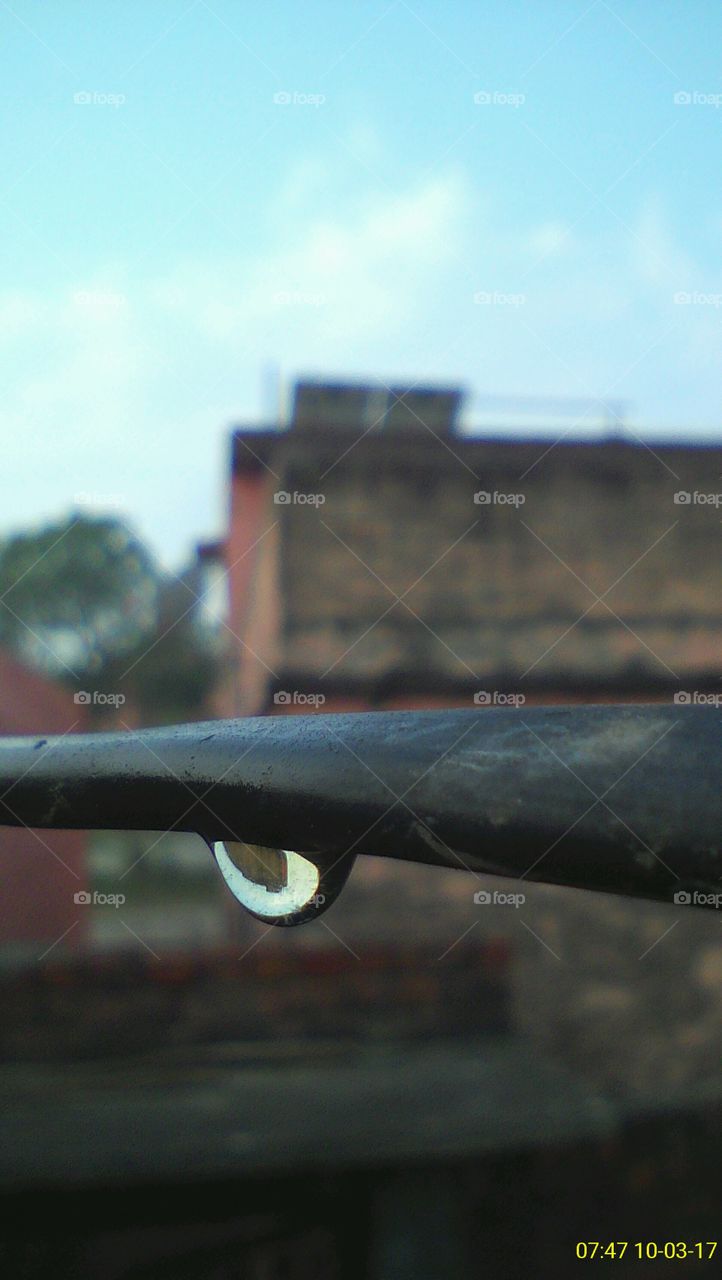 A water drop hanging from an electrical wire just after rainfall