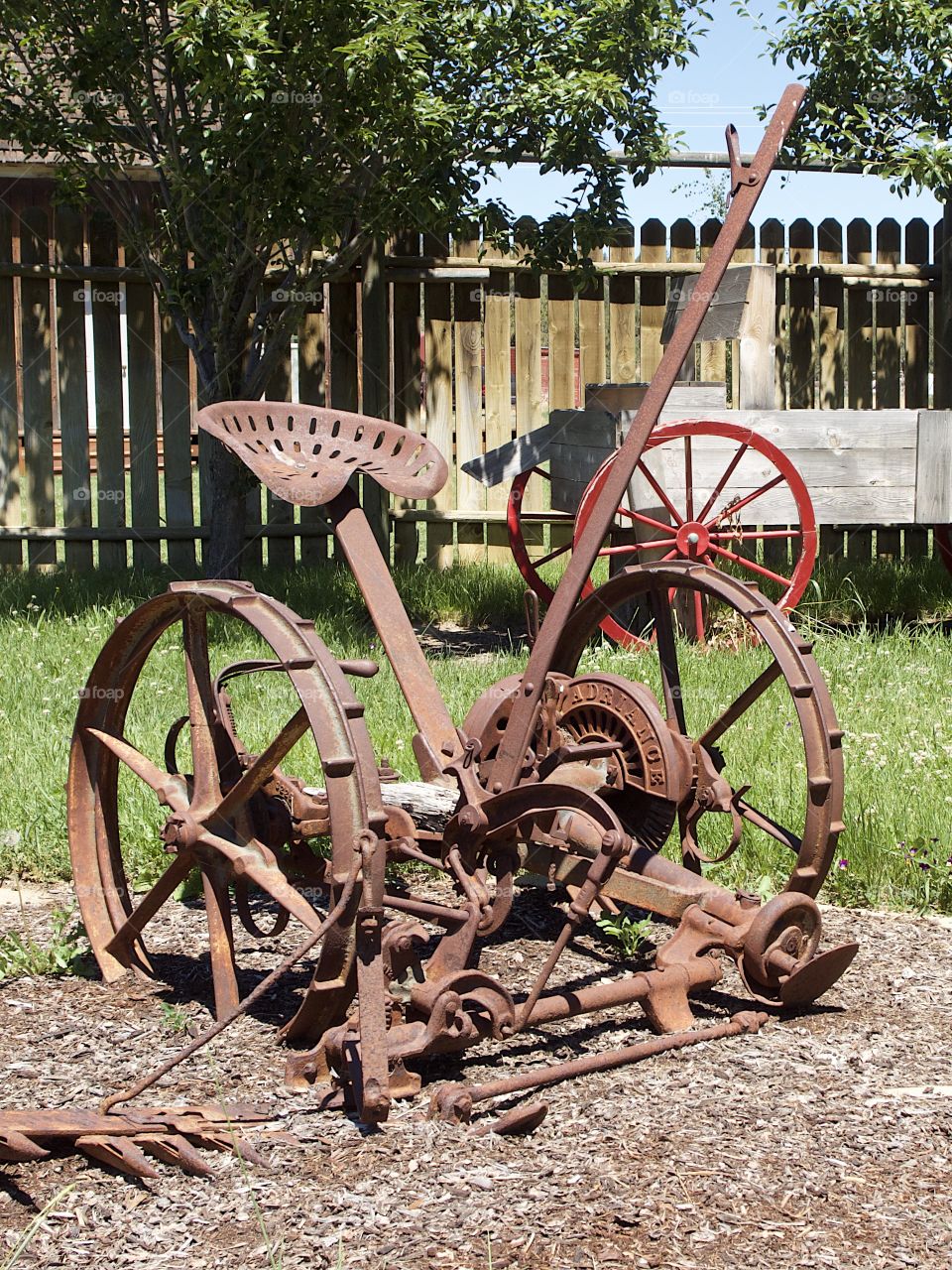 A rusted old field plow being used as an ornamental garden decoration in Central Oregon on a sunny summer day. 