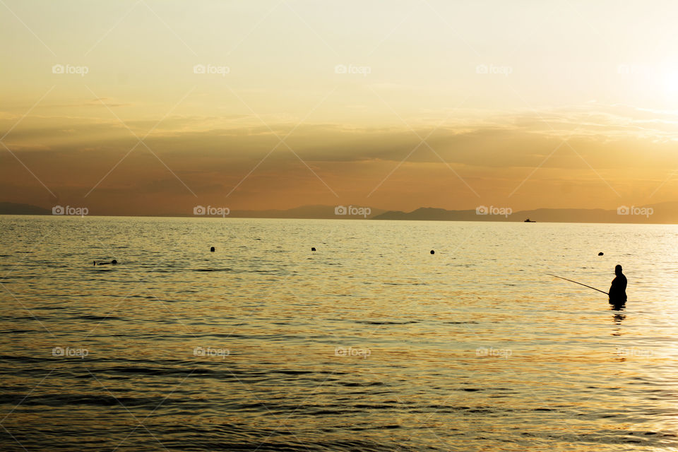 fisherman at sunset. fisherman in sea at sunset