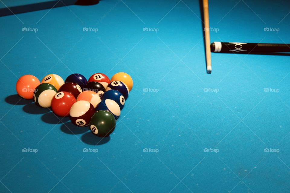 A Set of colourful balls and cue on the billiard Table .