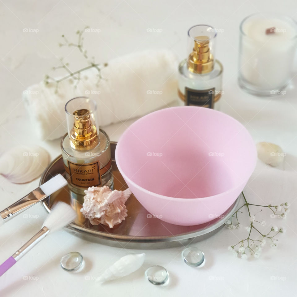 Preparation for home facial skin care. Cream, peeling, soap, bowl, brushes, towels, candles and shells on a white background. Spa salon at home
