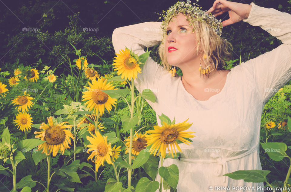 Elegant woman with crown in sunflower field