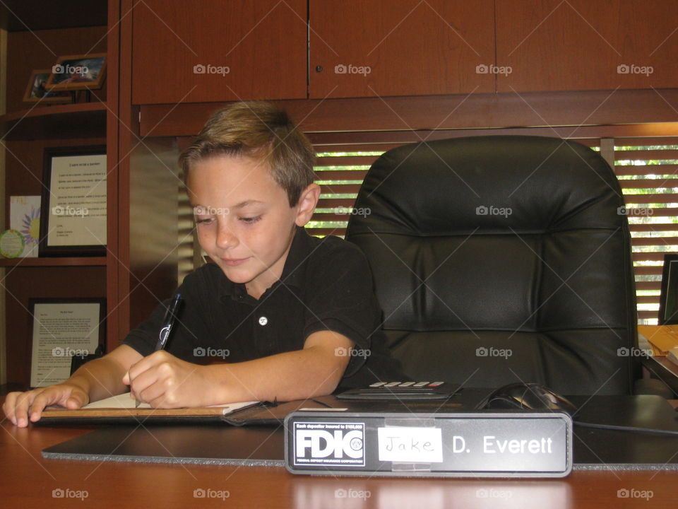 Businessman writing on paper at desk in office