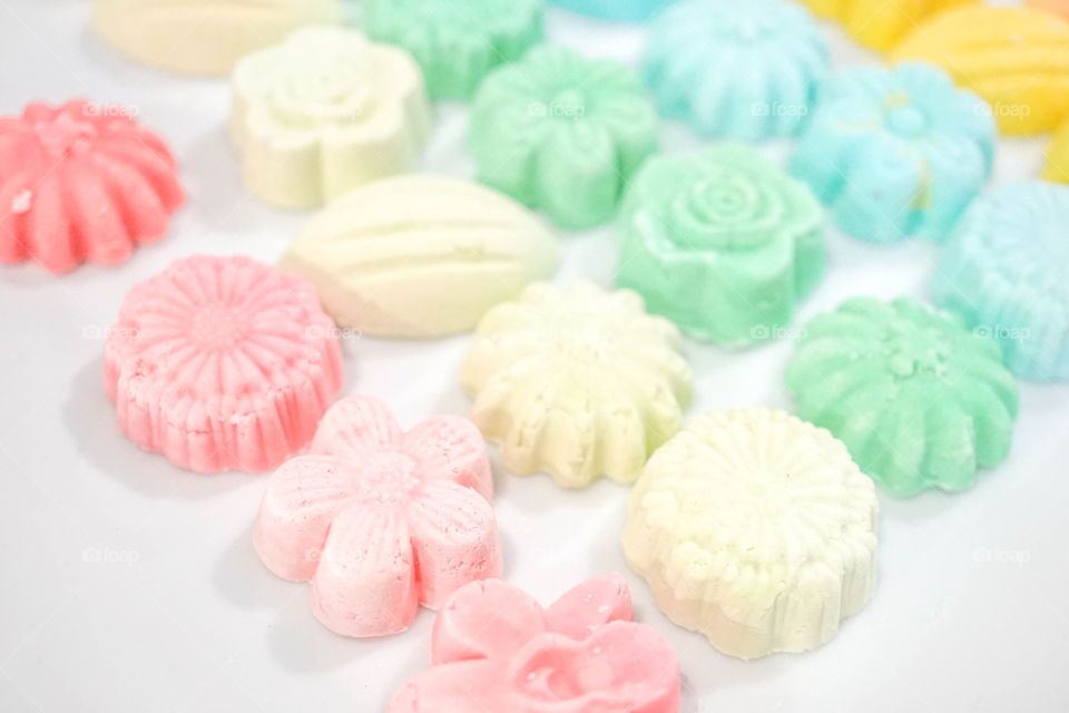 Thai sweets : Thai coconut cookies in sweet pastel colors of pink, yellow, green, blue and orange flowers. Thai coconut cookies or Kanom Sum Pun Nee. with soft focus on the pink second pink flower.