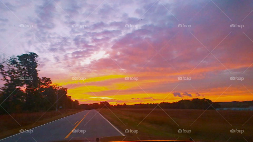 driving down a country road at sunrise.