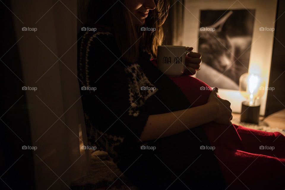 Pregnant woman enjoying a cup of tea in a diffuze light setting
