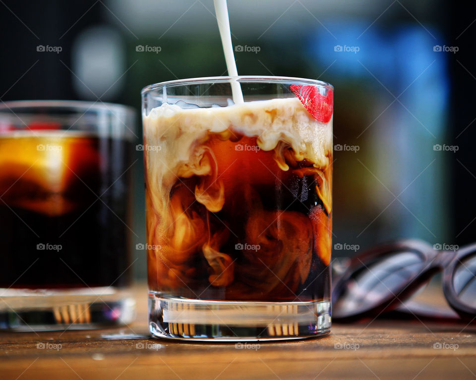Pouring milk into cold brew coffee on a hot summer day.