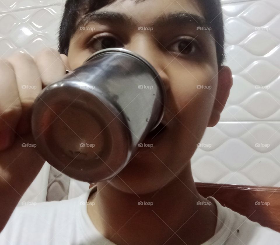 A boy is drinking from a dirty cup