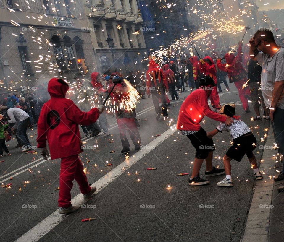 Barcelone festival correfoc red dressed kids running with firework in the street with crowd