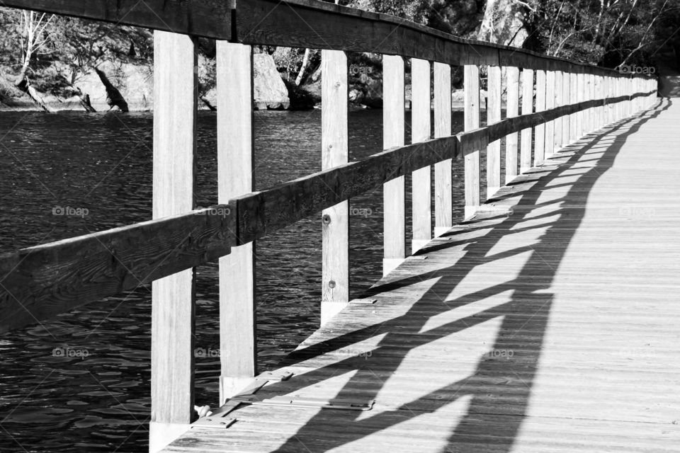 Shadows from wooden handrails on wooden pier crossing the lake , black and white 