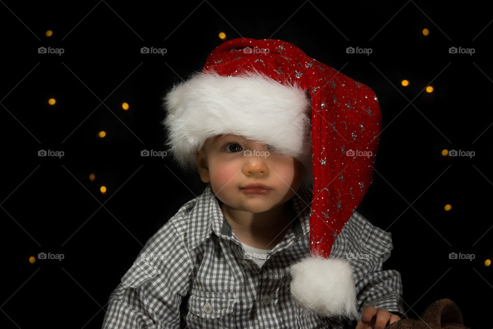 Portrait of a young boy with santa hat against black background