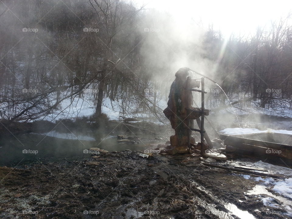 hot underground spring in winter in a forest glade