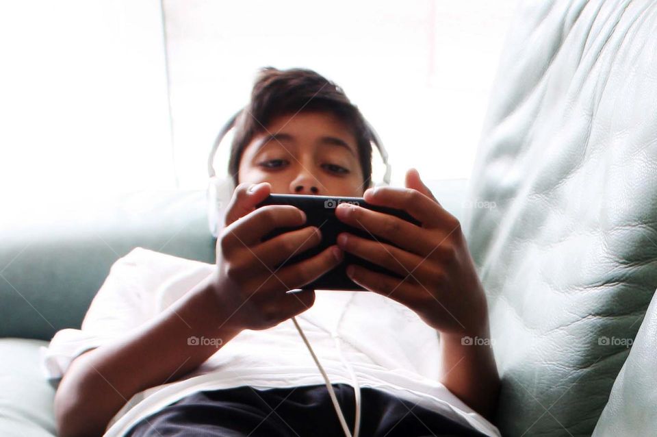 Teen boy is watching something on his phone