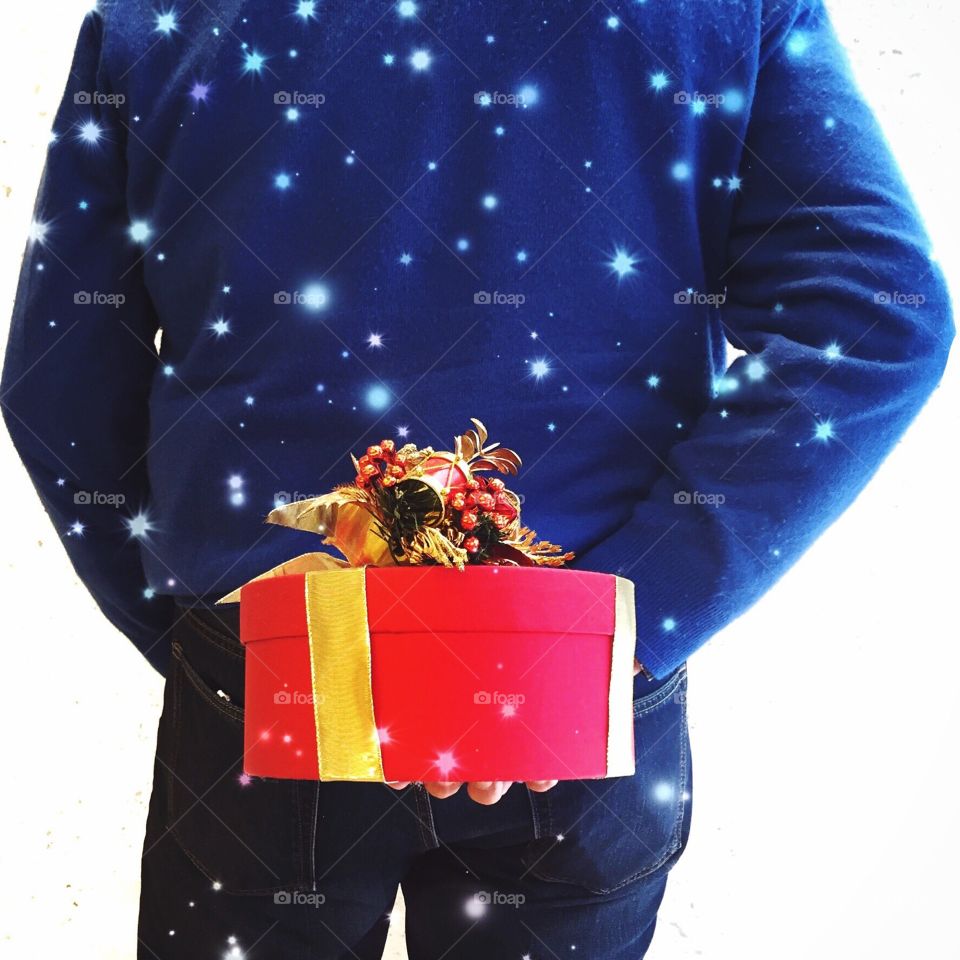 Man holding christmas present behind his back