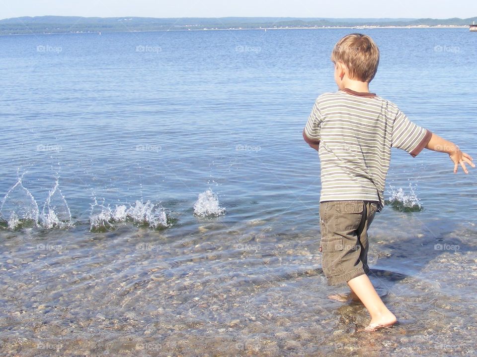 Boy tossing rocks, splash in water