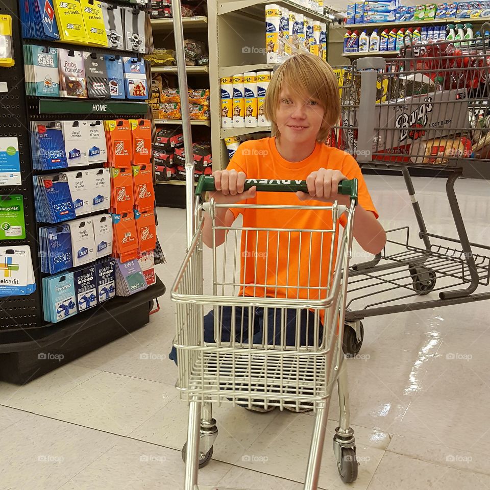 Teenage boy with trolley in supermarket