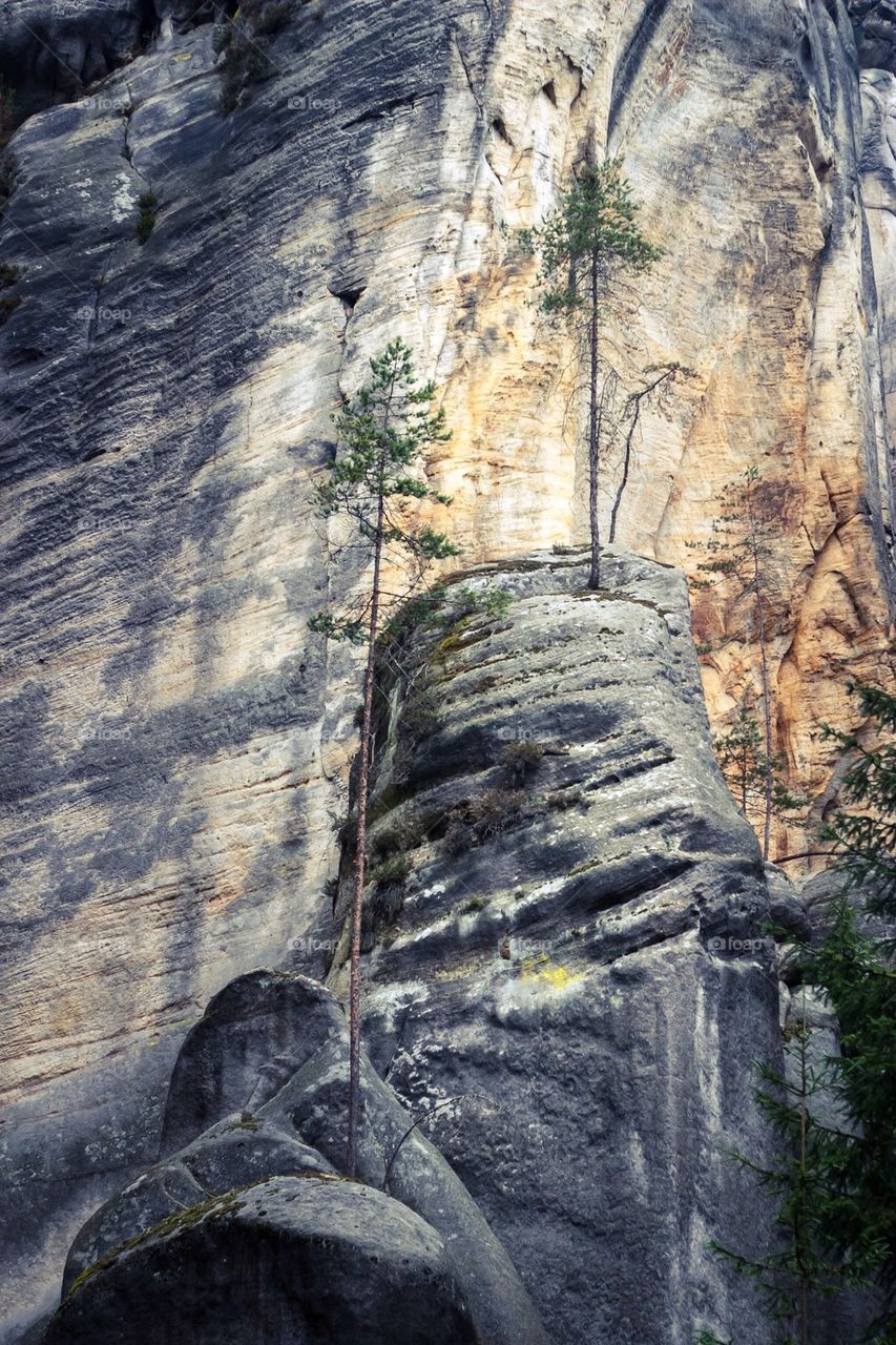 Stone peak standing against high rock wall