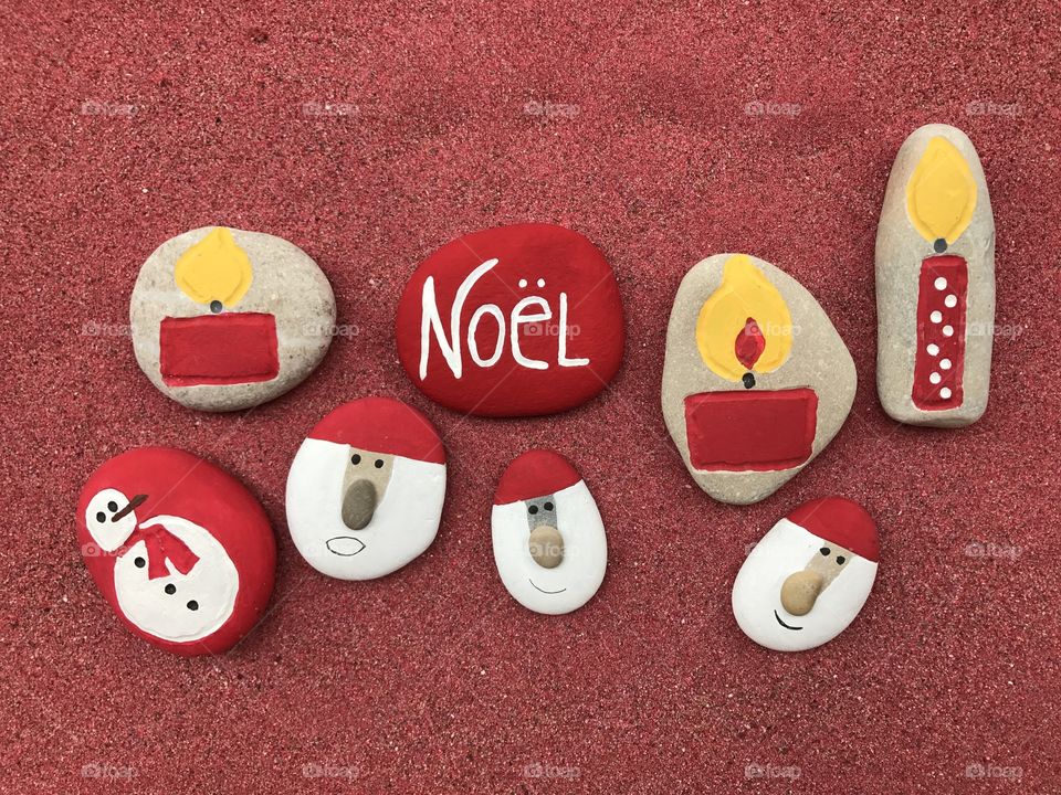 Noël, french Christmas word with stones composition over red sand 