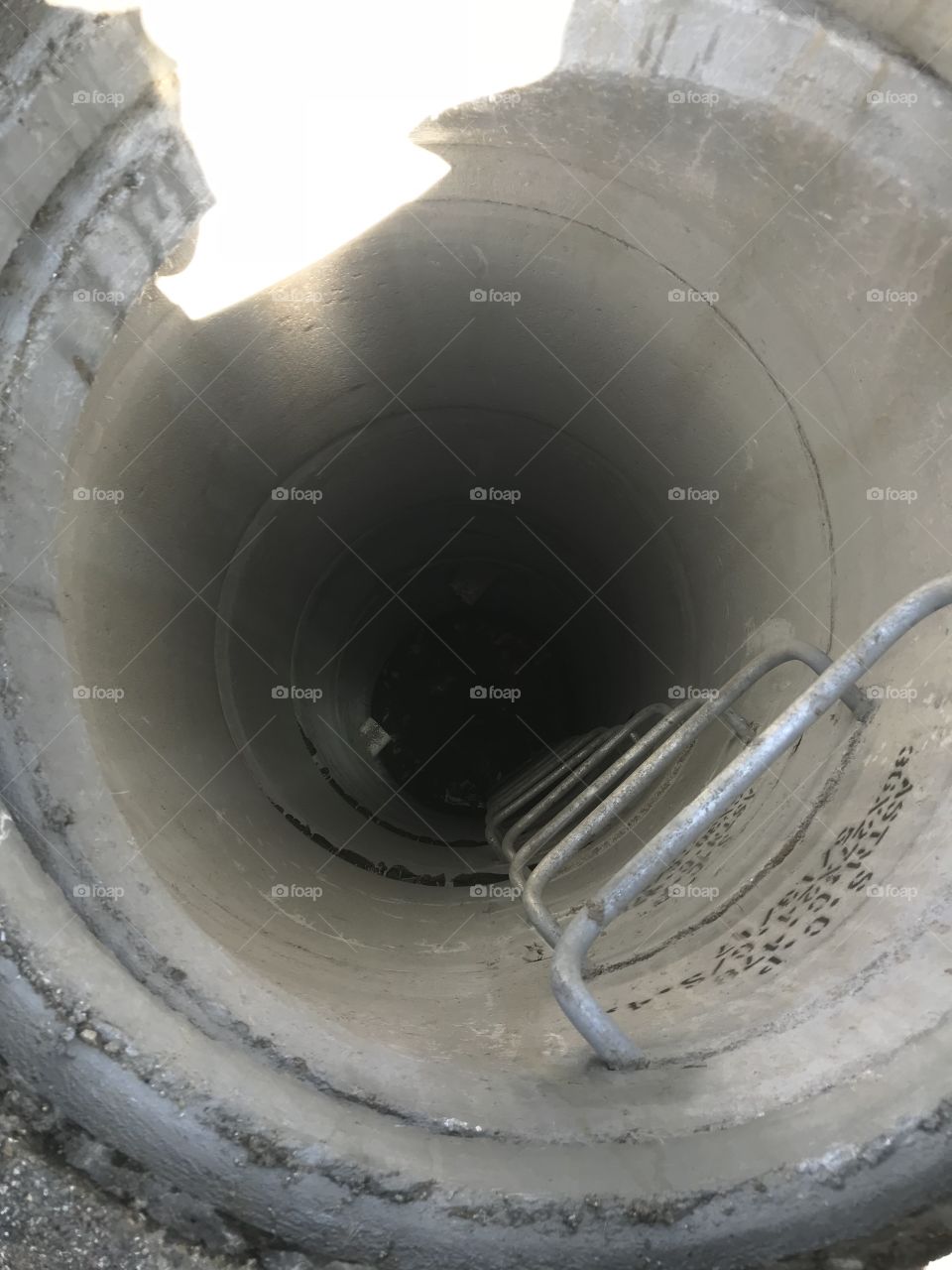 Inside a clean manhole. Looking down into the dark. 