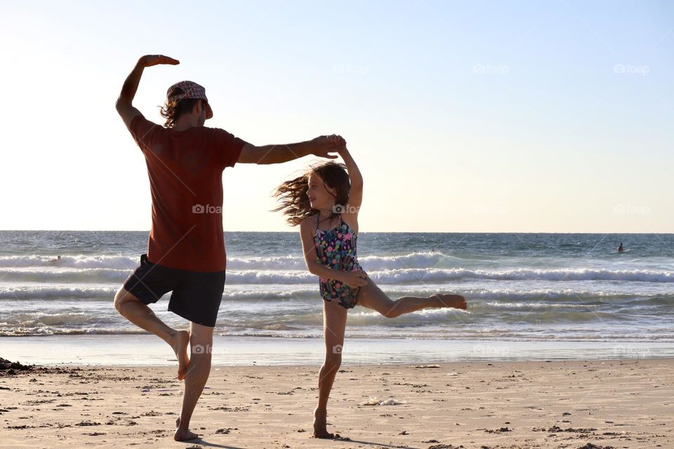 Father and daughter dancing on the beach 