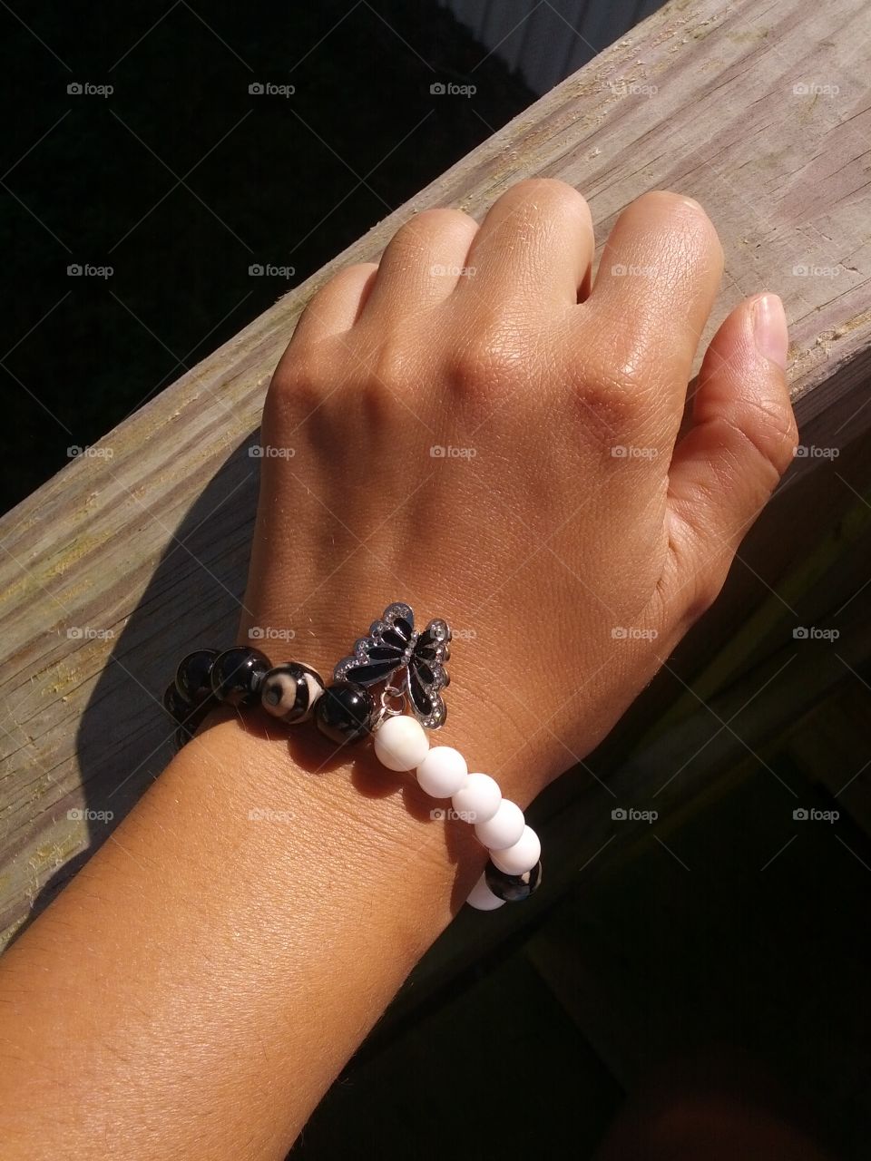 Beautiful black and white bracelet with a butterfly attached to it