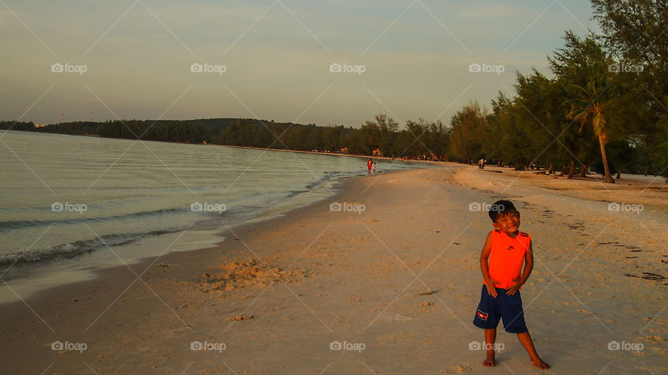 The boy is standing a long quiet beach