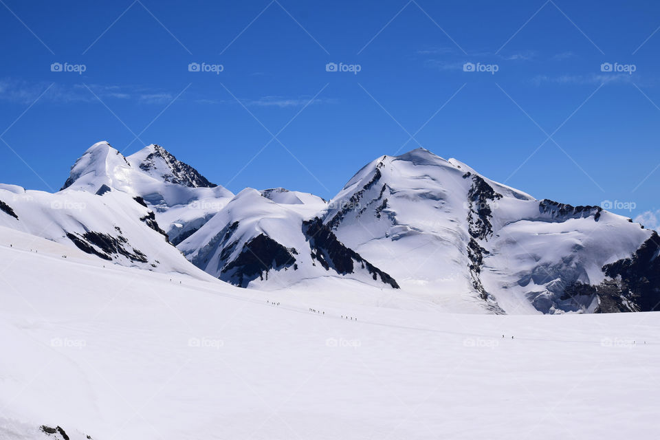 Snow in the mountains with people skiing  appearing like ants :)