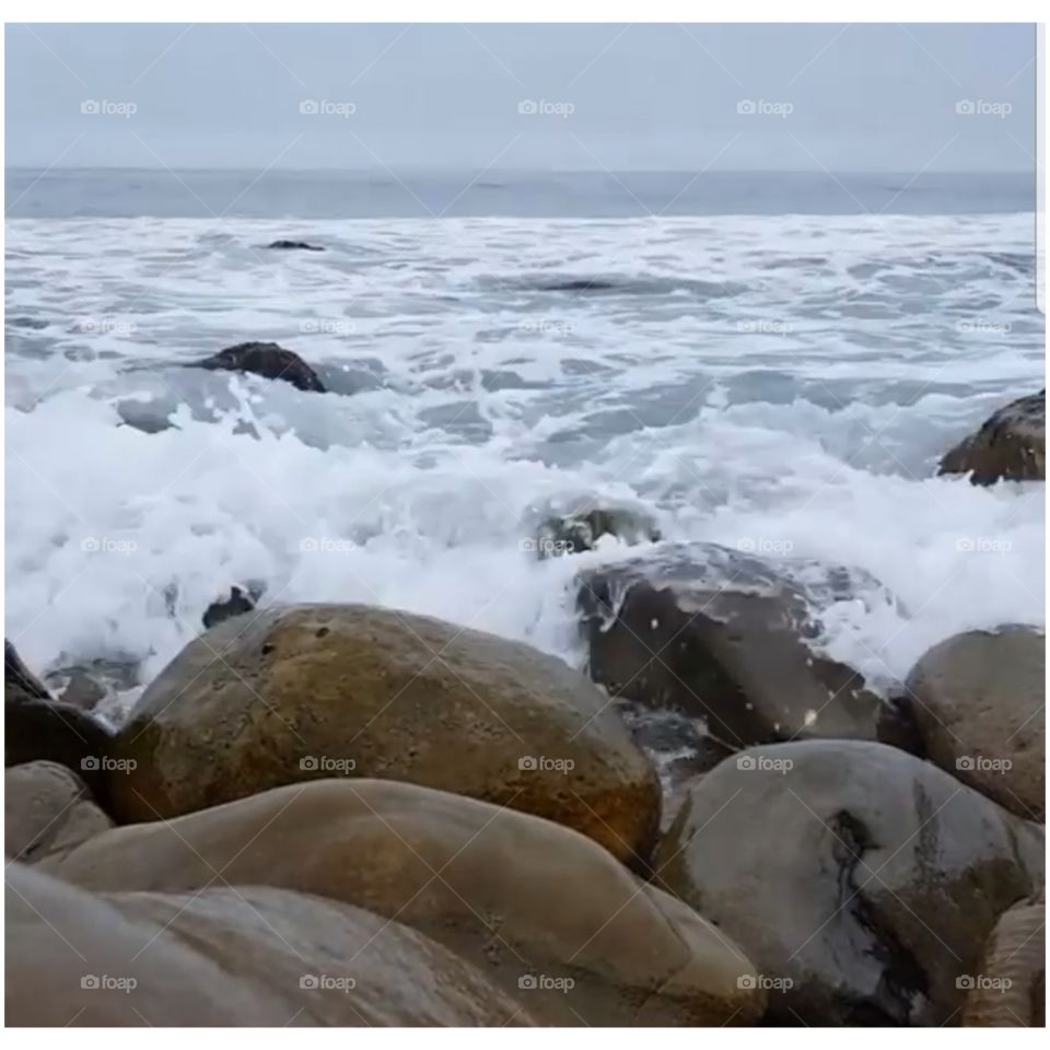 waves crashing into shore against big rocks