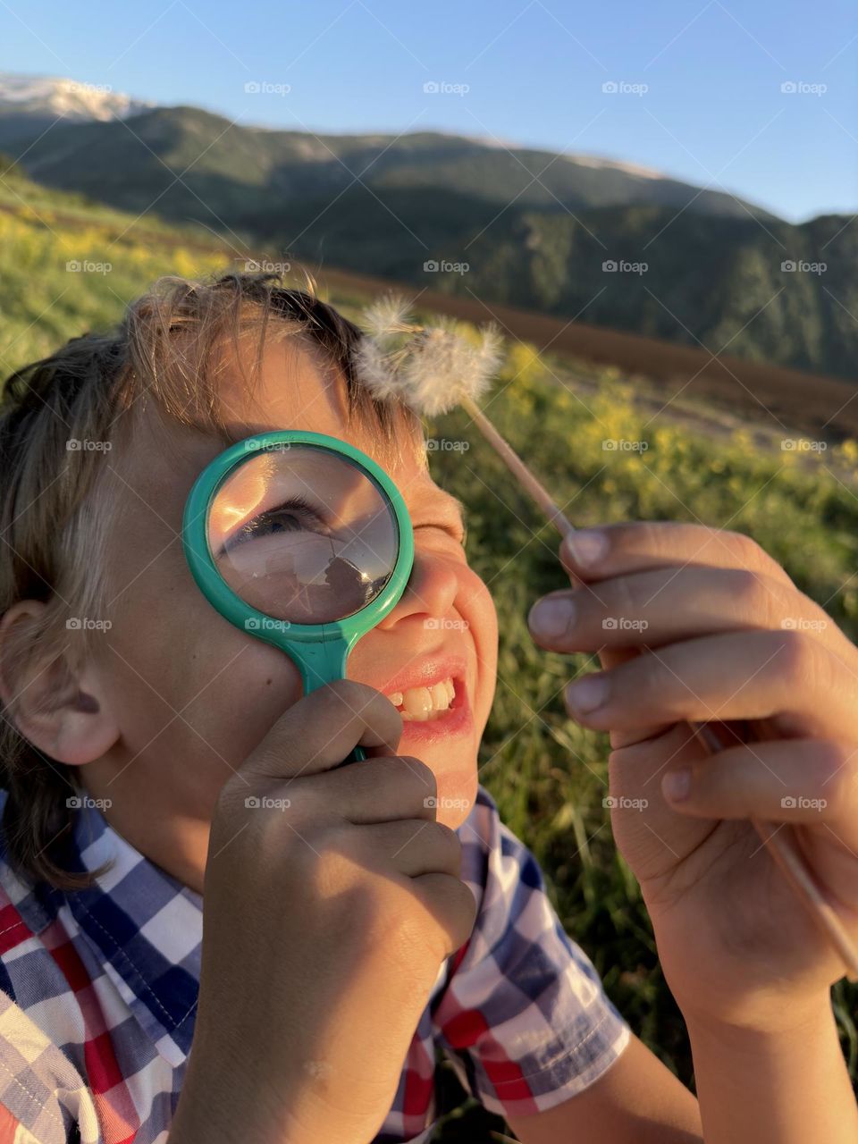 boy looking through a magnifying glass at a flower