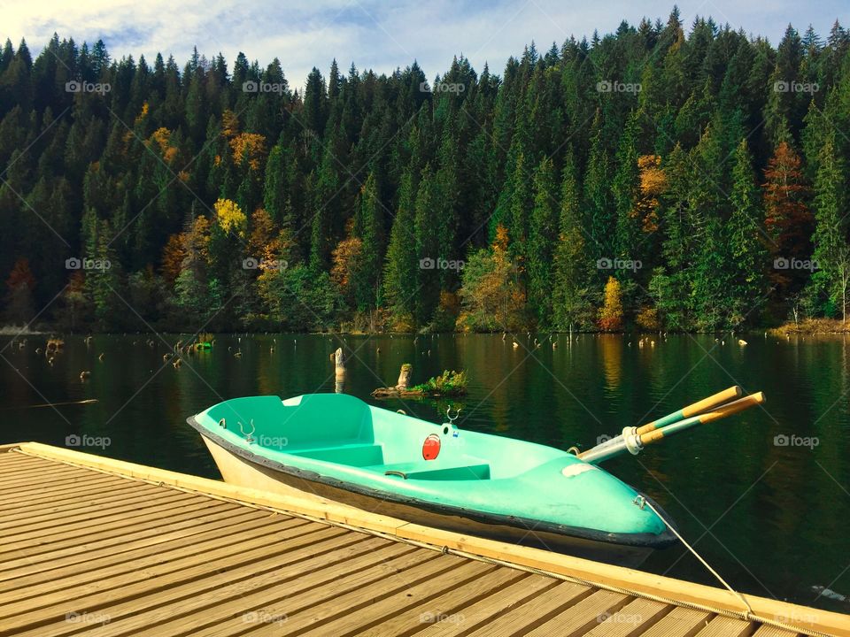 Paddleboat on the lake surrounded by forest in autumn