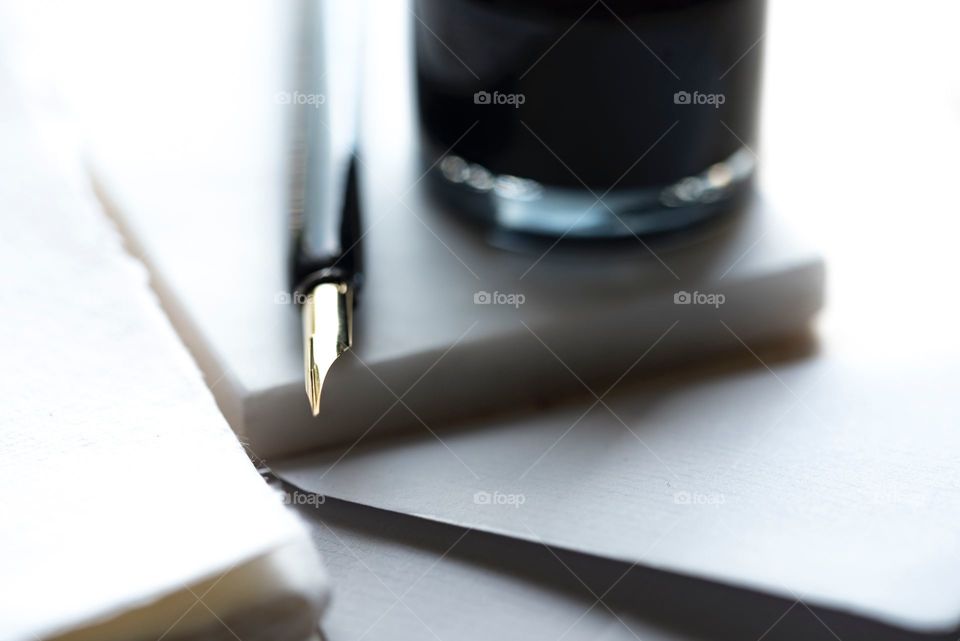 a glossy tip of a fountain pen next to a drinking glass