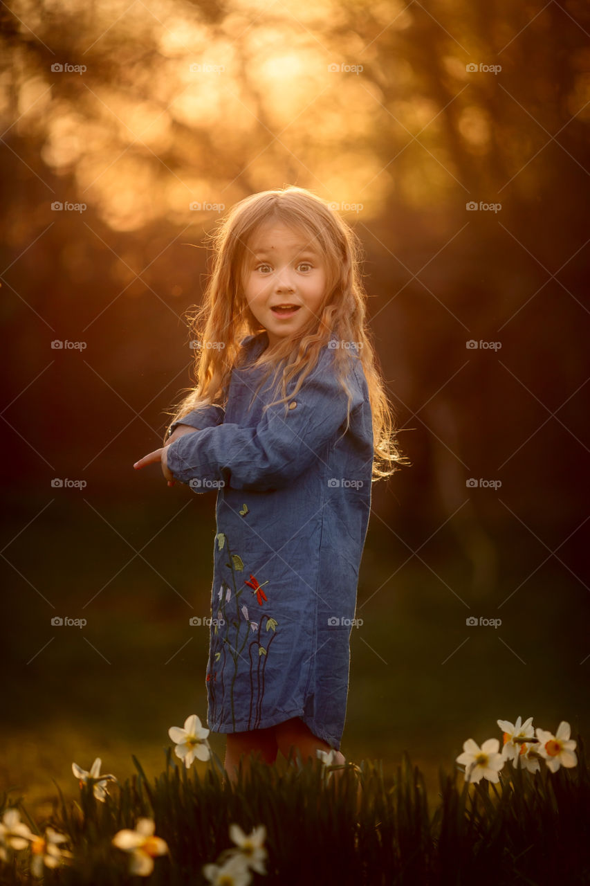 Little girl with narcissus at sunset