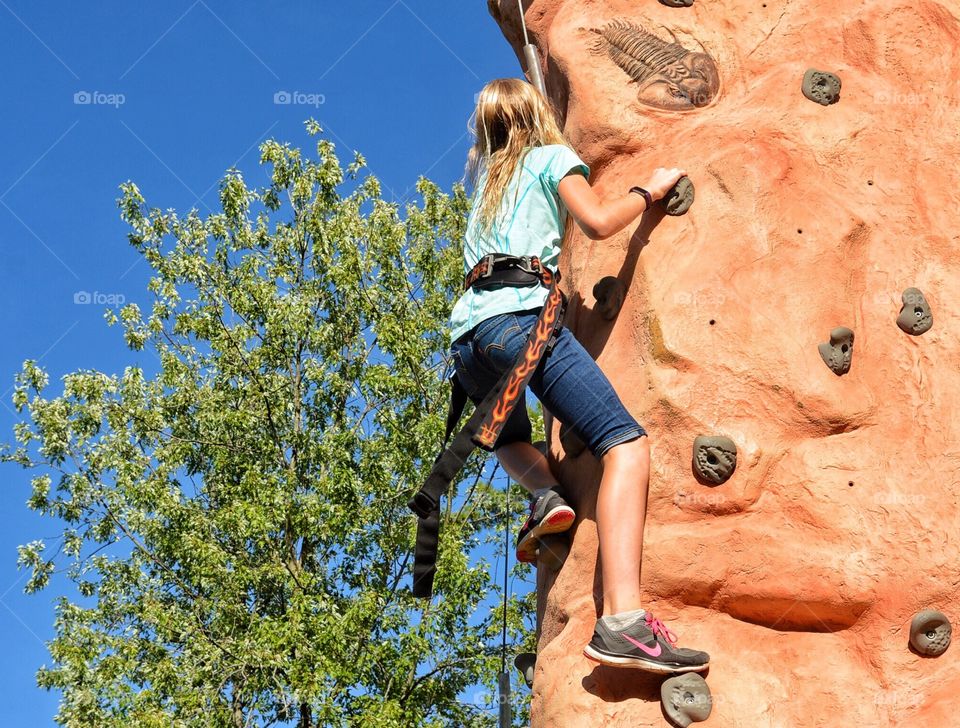 Teenager climbing rock wall