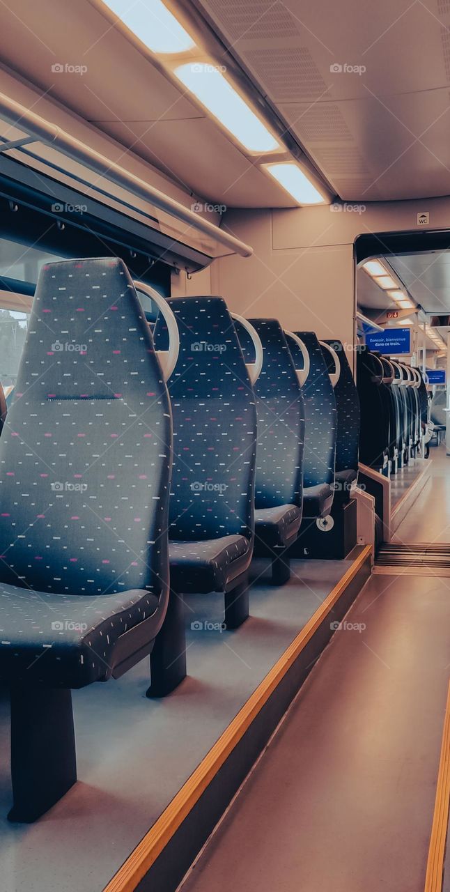 Soft textile blue chairs inside a European train rhythmically diagonally, close-up side view.