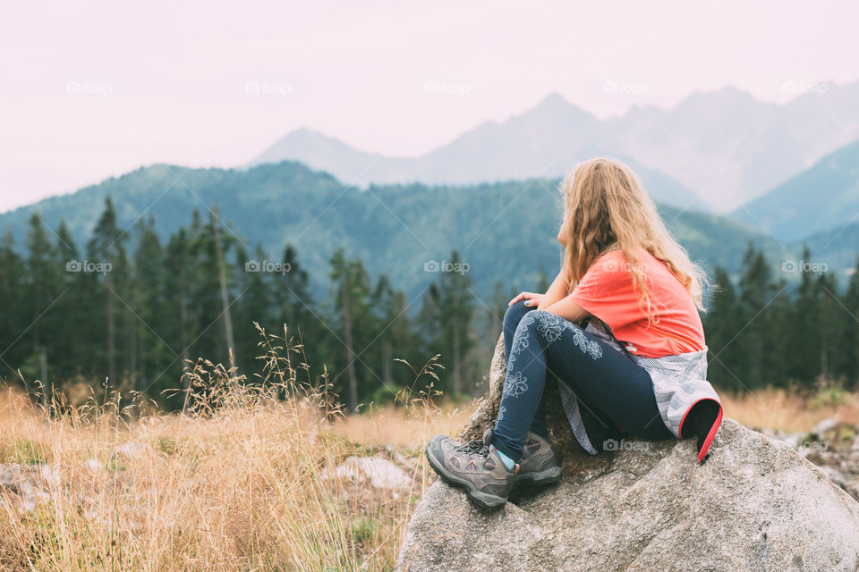 Girl sitting on a rock. Girl sitting on a rock and conteplating mountain  landscape in The Tatra Mountains