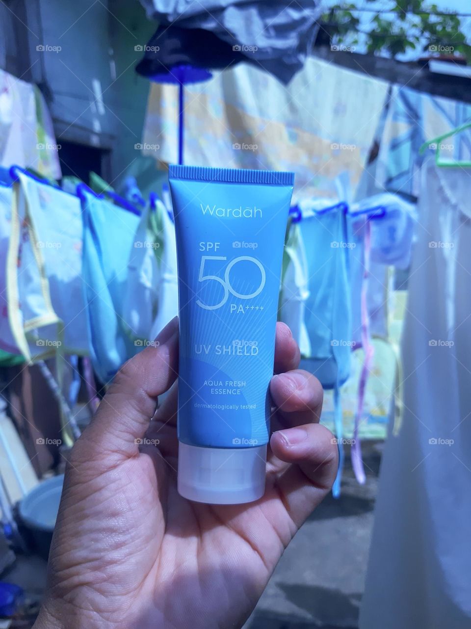 Hand holding Wardah beauty product, UV protection.